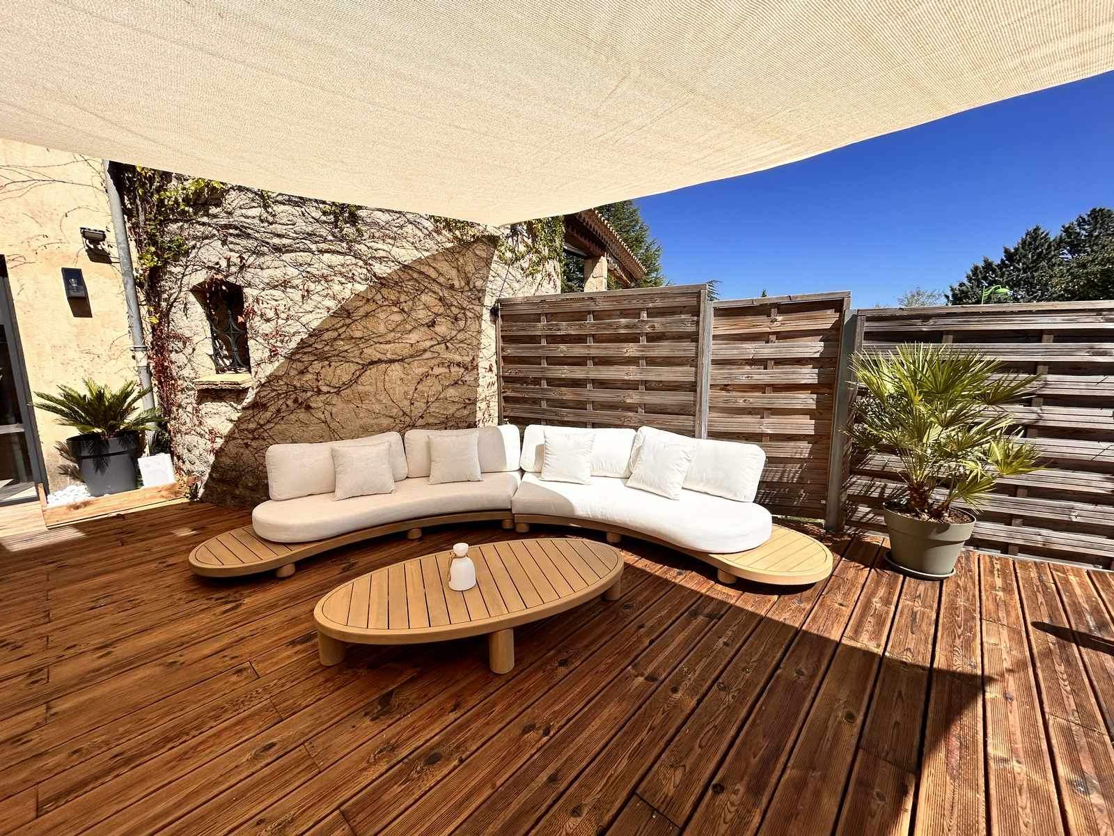 La terrasse en bois du Clos des Elfes sous la voile d'ombrage